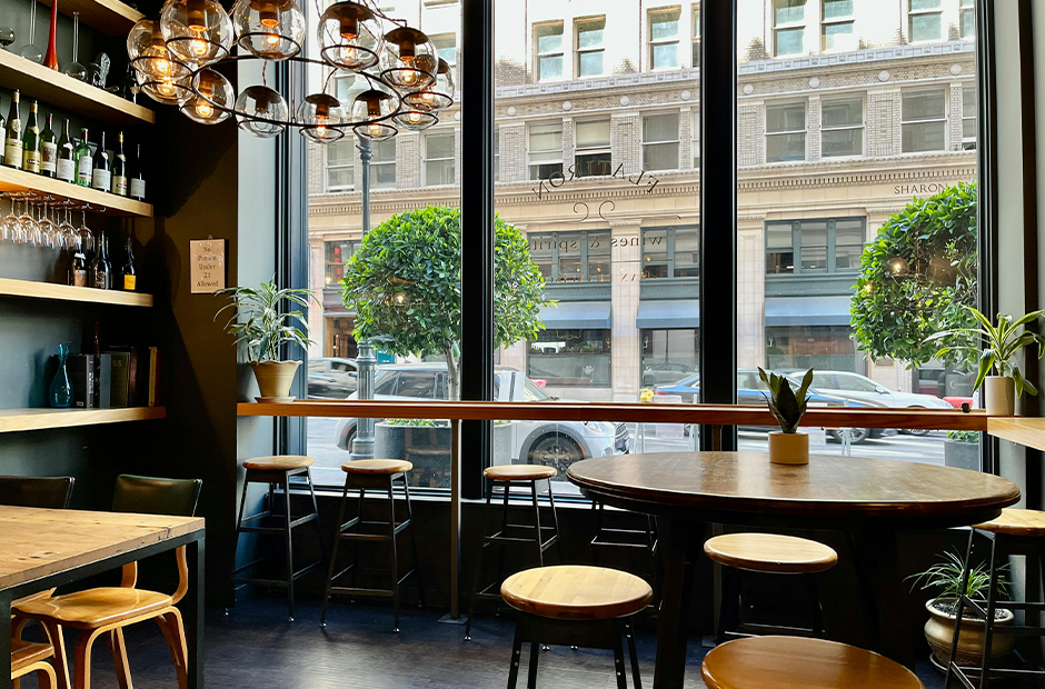 Brown Wooden Table and Chairs beside Glass Wall in a City