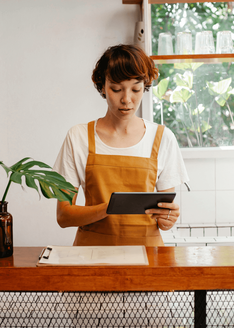 Restaurant worker standing behind the counter working on a tablet. Restaurant worker standing behind the counter working on a tablet.
