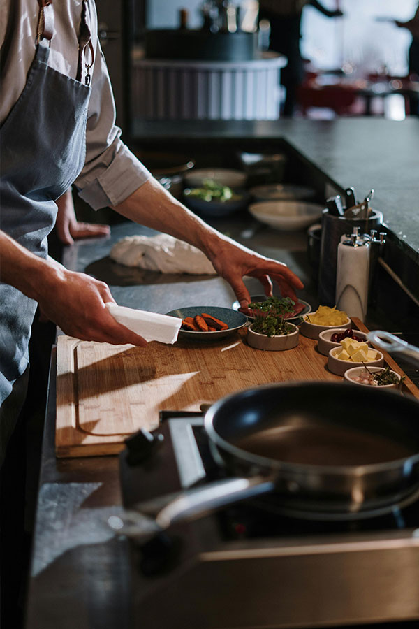 Person in White Apron Holding White Ceramic Plate
